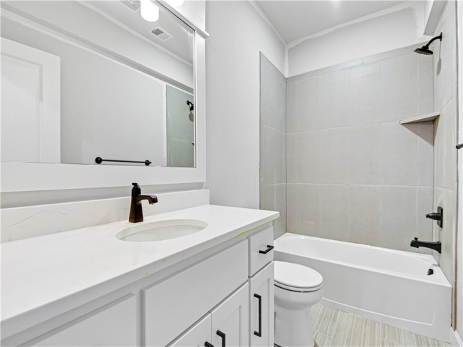 Full bathroom with tile flooring, vanity, toilet, and tiled shower / bath combo