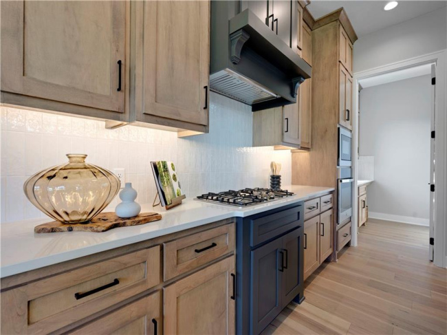 Natural wood cabinetry and custom solid surface countertops define this modern cooking space.