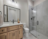 Tiled walk-in shower complements a warm wood vanity in this sleek bathroom.