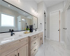Polished tile flooring and double vanities anchor this beautifully detailed primary bathroom.