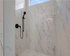 Elegant marble-patterned tile lines this modern shower featuring sleek matte black hardware.