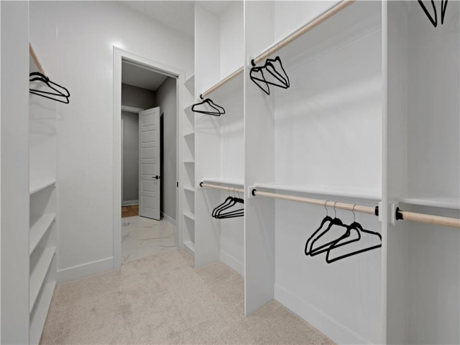 Custom built-in shelving and ample hanging rods maximize organization in this plush carpeted closet.