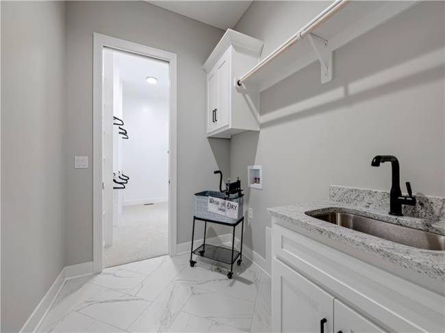 Polished tile flooring and a built-in utility sink elevate this functional laundry space.