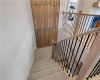 Carpeted stairs lead downward past a distinctive wood accent wall and contemporary metal railings.