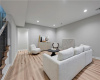 Smooth recessed lighting illuminates this versatile lower level space featuring warm hardwood flooring.