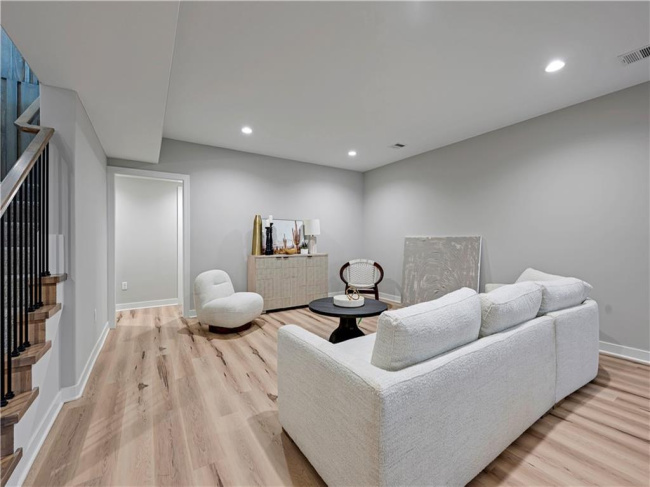 Smooth recessed lighting illuminates this versatile lower level space featuring warm hardwood flooring.