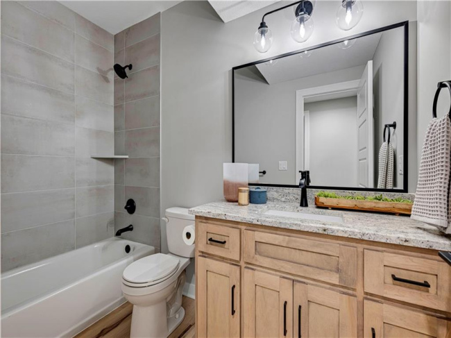 Natural wood cabinetry and polished granite counters anchor this modern bathroom space.