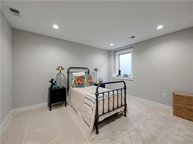 Recessed lighting and soft carpeting create a cozy atmosphere in this quiet basement bedroom.