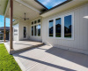 An inviting covered patio steps down to a concrete terrace overlooking the yard.