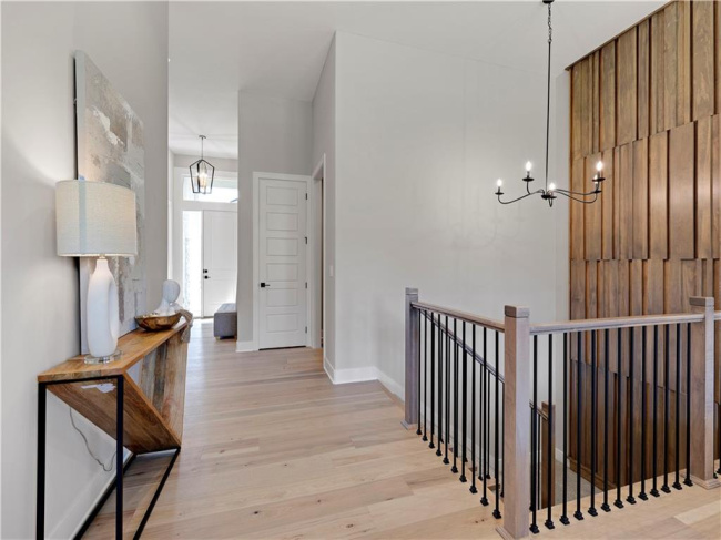 Smooth wood floors and tall ceilings define this airy upper-level landing and hallway.