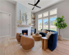 Sunlight streams through towering windows into a welcoming living space anchored by a stone fireplace.